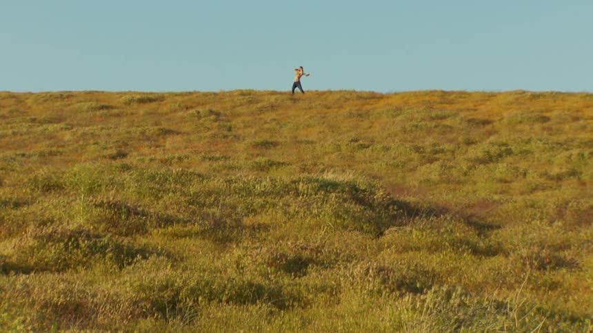 A person dances on a grassy plain