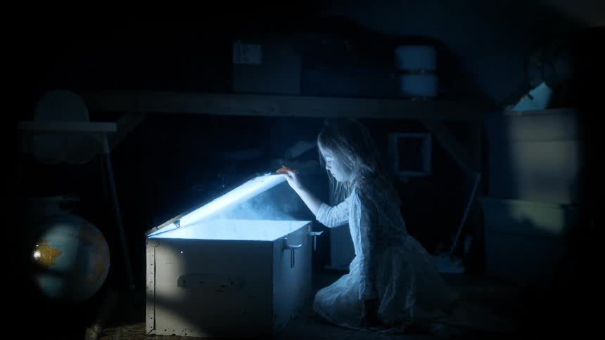 A child opens a chest in the dark room