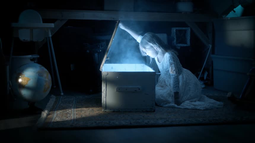 Girl in a dark room looking at an open wooden box that emerges a strong white light with smoke