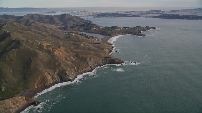 An aerial view of a coastline with steep cliffs next to a large suspension bridge