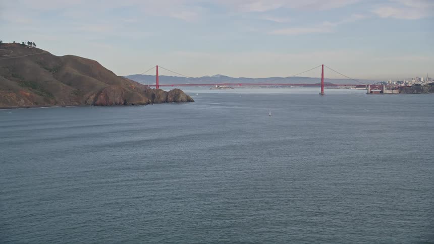 Panorama of rocky seaside coast with golden bridge on horizon