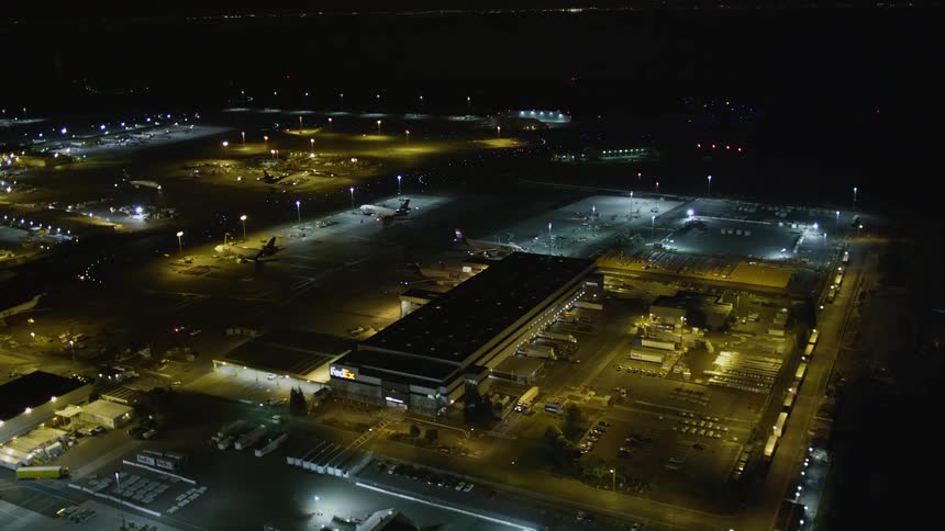 An aerial view of an airport building with several parked planes on a night