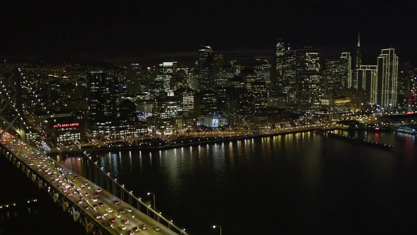 Rippling water gives way to a giant bustling city at night