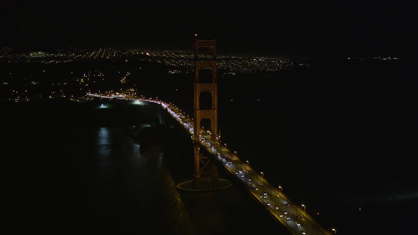 Aerial scenery of a long bridge illuminated at night with vehicle traffic
