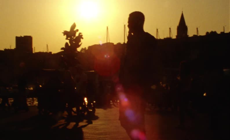 Street in a city by the sea illuminated with solar reflection in the late afternoon and silhouette of pedestrians walking