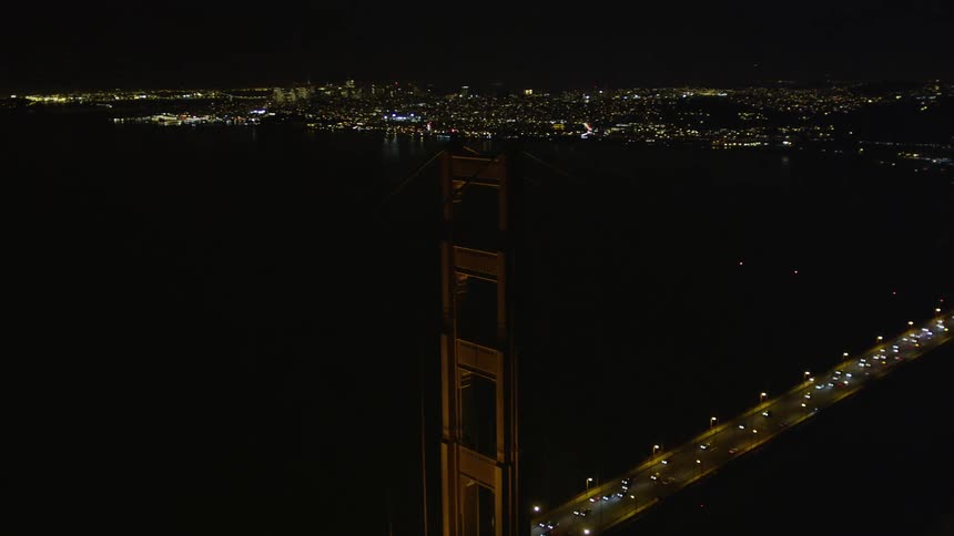 Panorama of a long bridge with vehicle traffic at night and a metropolis on the horizon