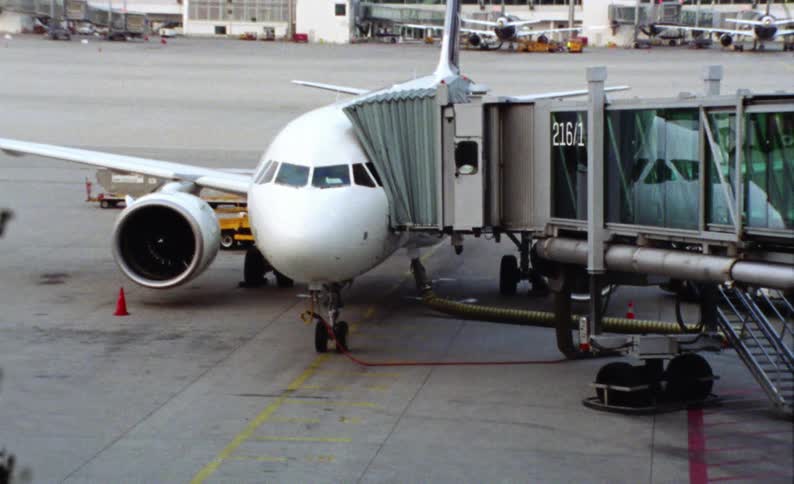 A white airplane is parked on a tarmac next to a passenger boarding bridge