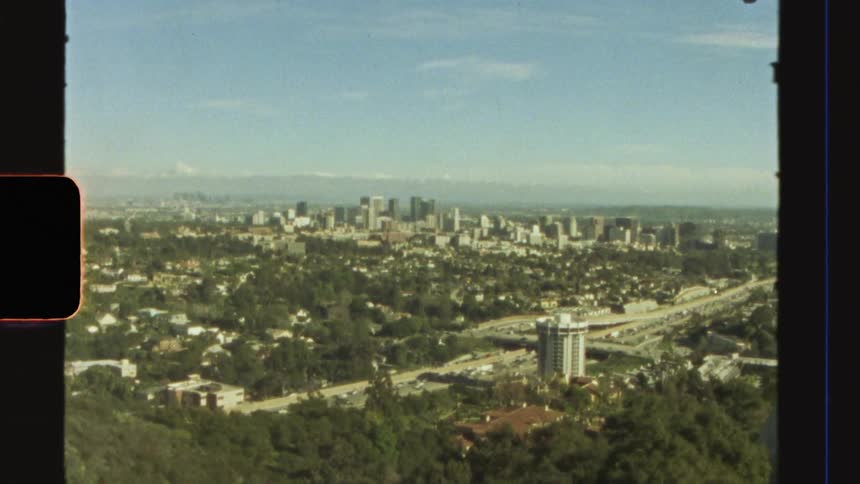Aerial view of a city surrounded by greenery under a clear sky caught on vintage film