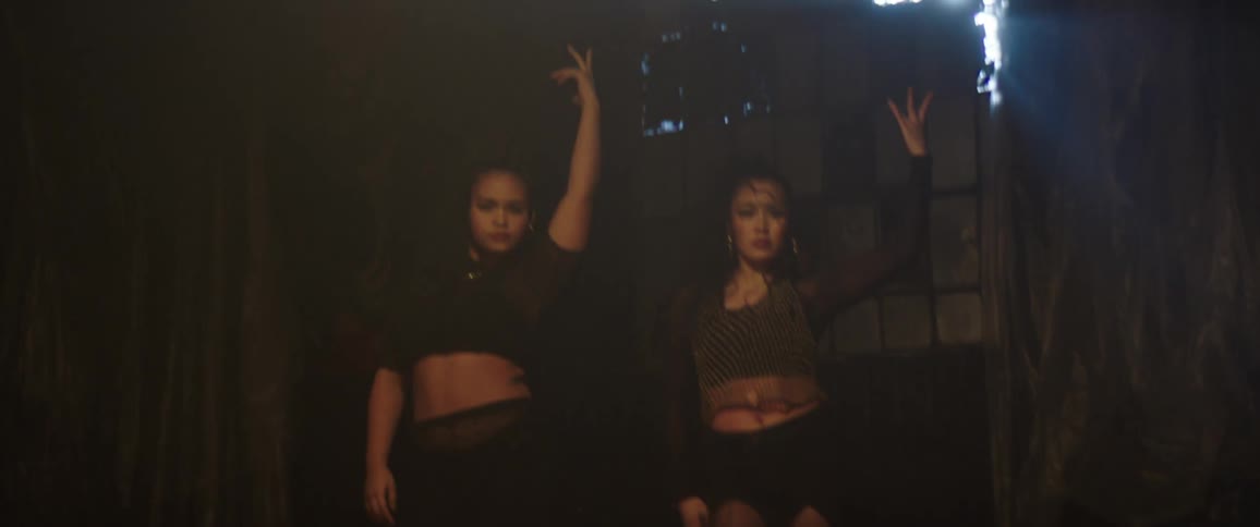 Two women are dancing in the dark room
