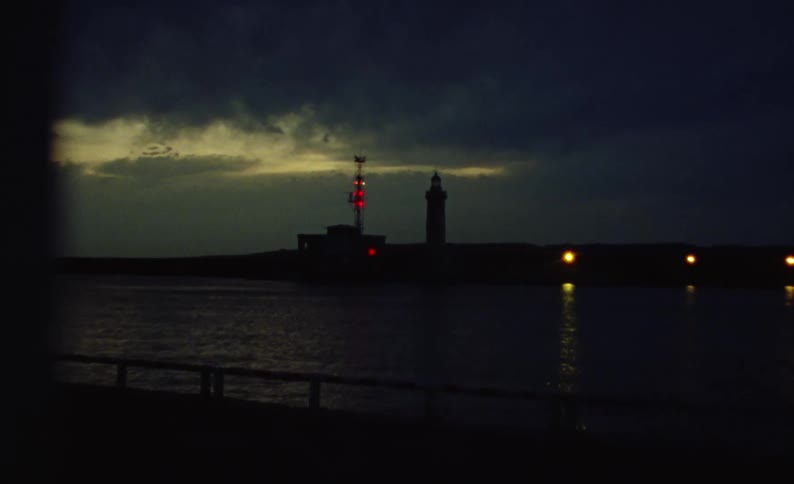 Lighouse on a harbor at night by the sea