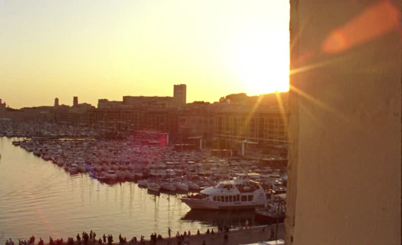 Panorama of an urban city around a sea canal with a harbor with moored boats and yachts and pedestrians walking in the late afternoon with a sunset on the horizon