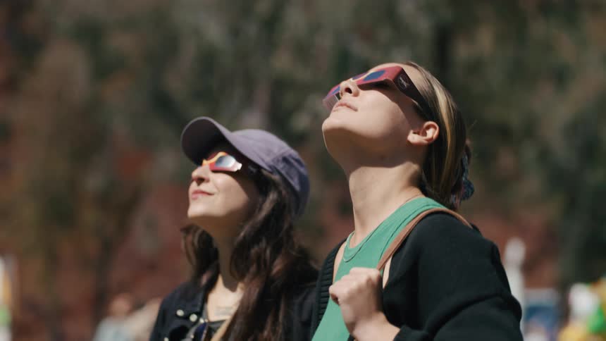 Two women wearing 3d glasses and looking up in an openair environment