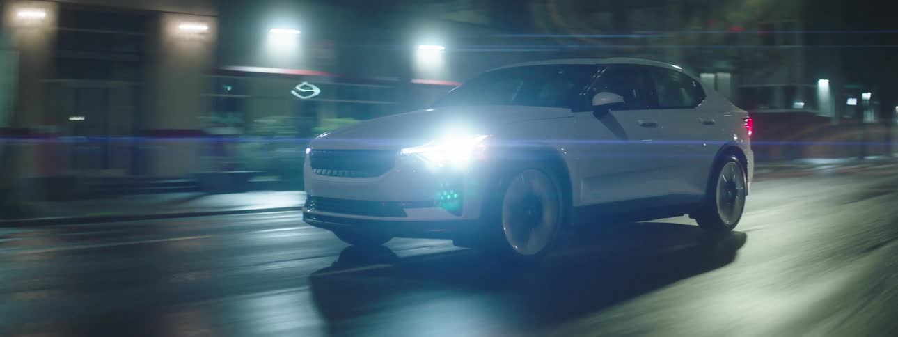 A white car driving on a city street at night