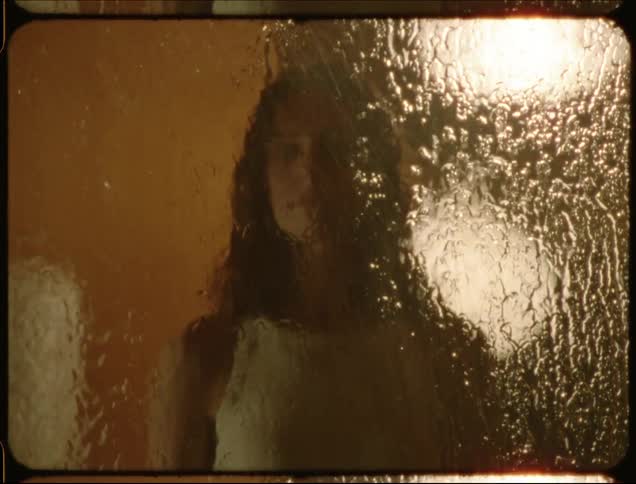 A woman presses her hand against a window on a rainy night