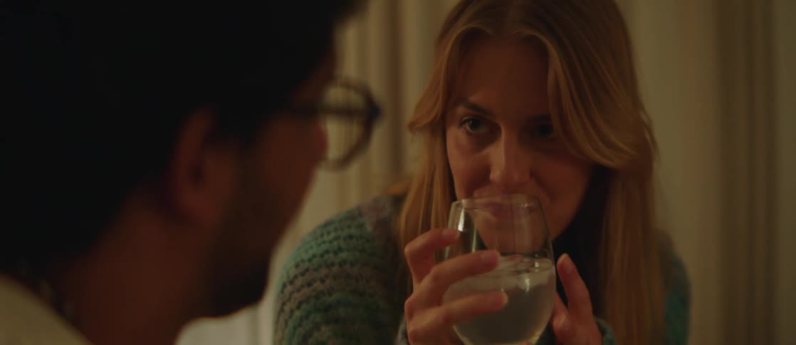 A woman takes a drink of a glass of wine