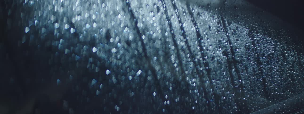 Rain falls and beads on glass