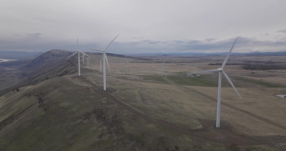 Multiple wind turbines generating energy on a hill side next to a river