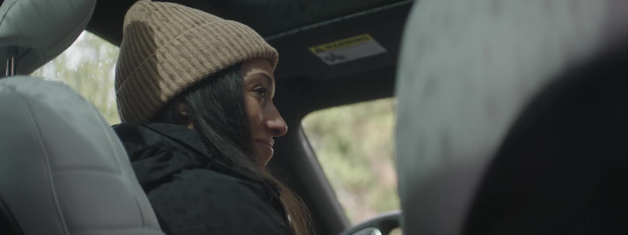 A black woman smiles and starts to exit a car