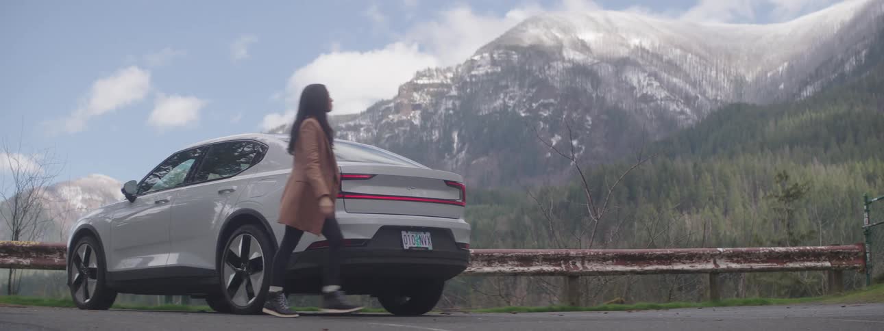 A woman parked on the side of the road walks over to look at the scenery