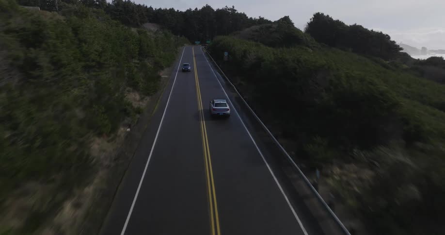 Cars driving down two lane highway next to the ocean