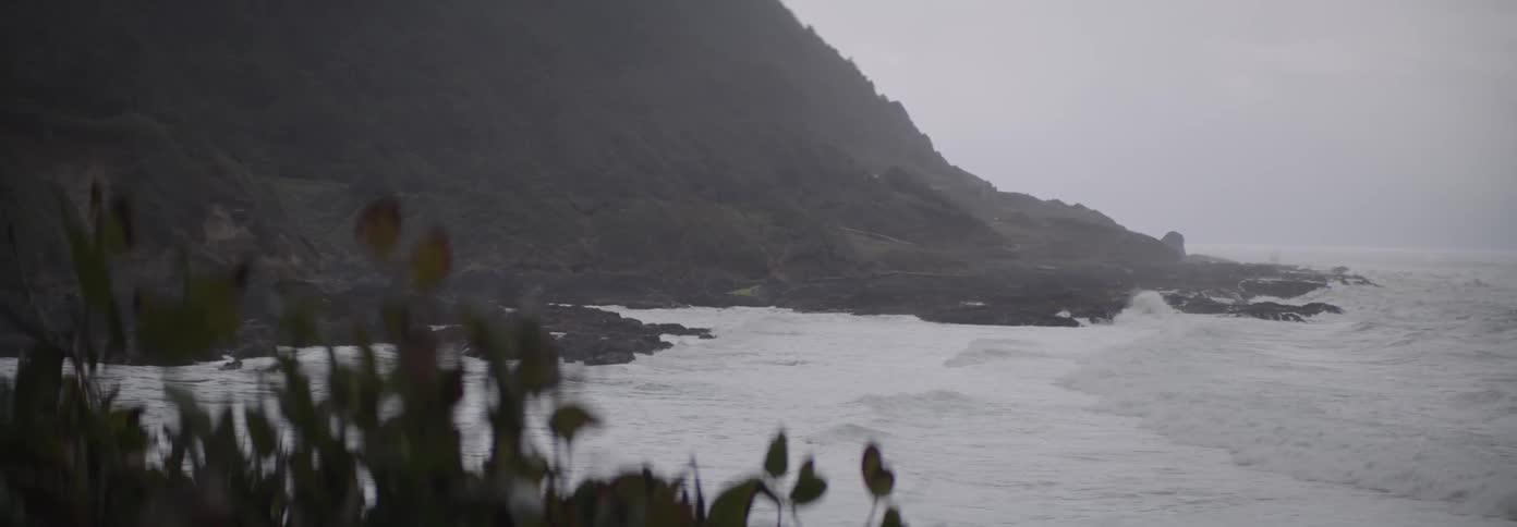 A rocky coastline with waves crashing against the shore under a cloudy sky