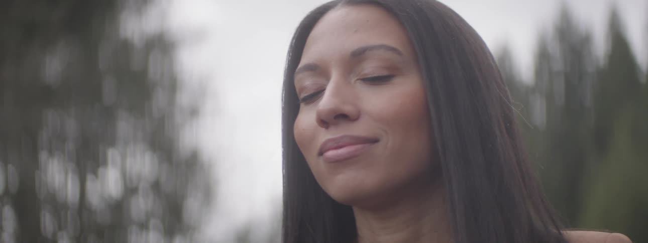A young woman with straight long hair relaxes in the forest
