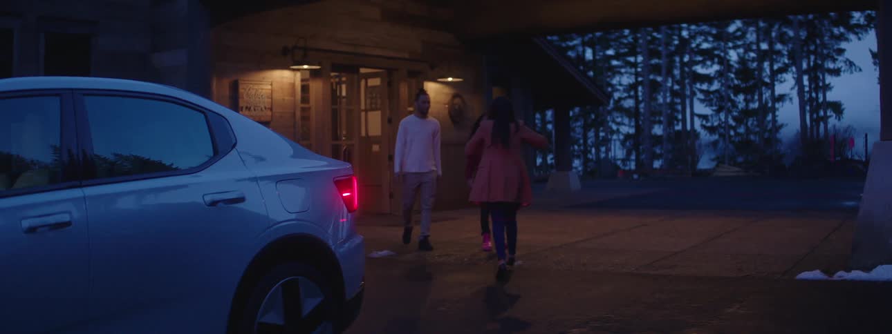 A woman gets out of her car and hugs a friend