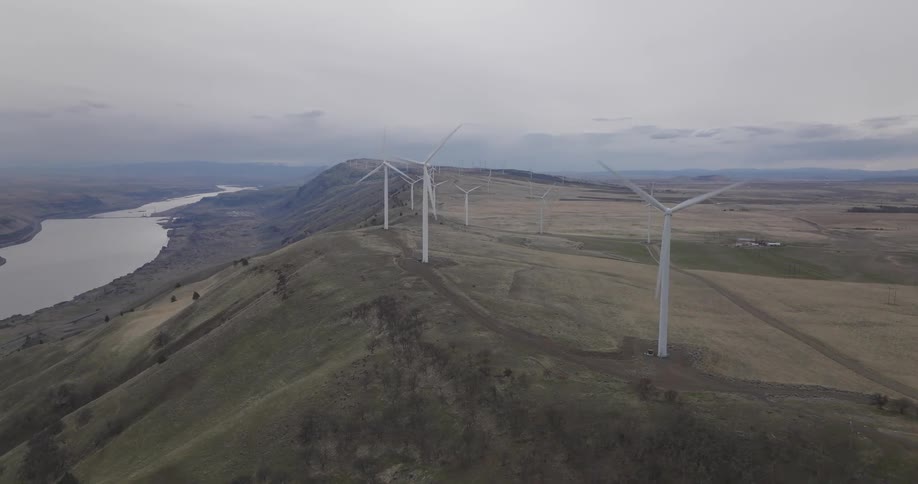 Aerial view of wind turbines spinning over a hill in the countryside