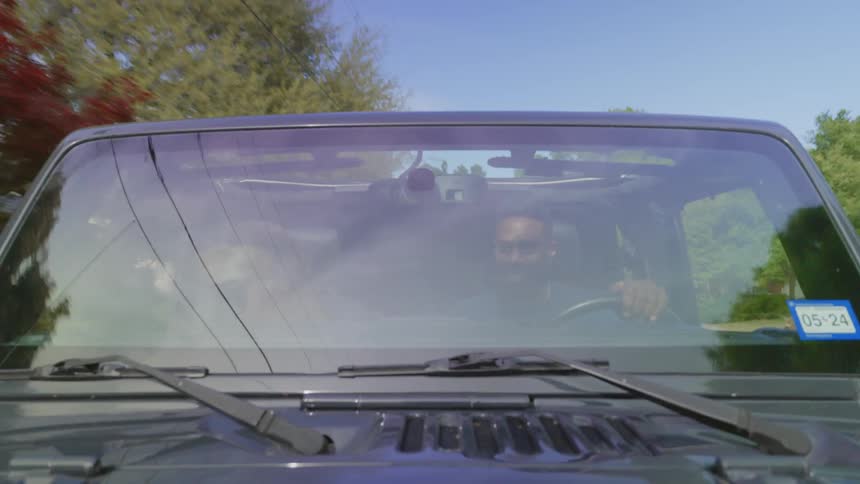 Exterior view of the windshield of a vehicle of a man driving accompanied by a dog at his side