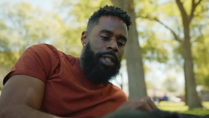 Man lying in a park petting his dog