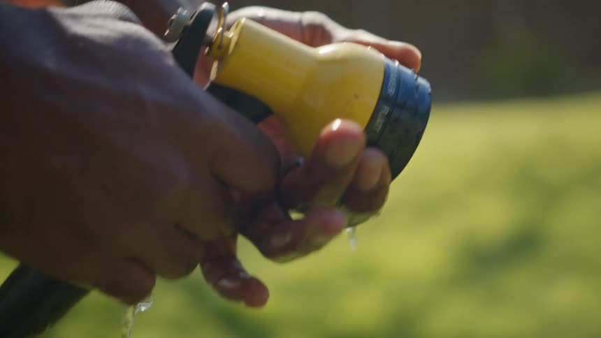 A man adjusting hose settings in the yard