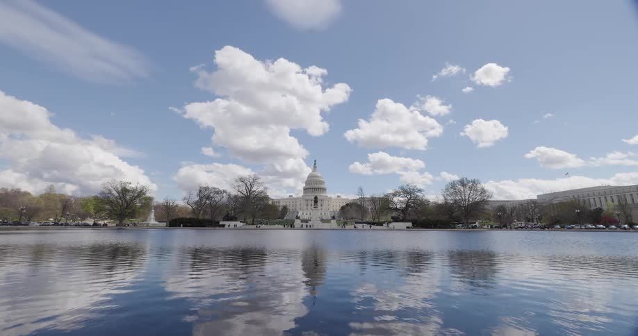 Panorama of a lake with people walking around it and the washington capitol in the background
