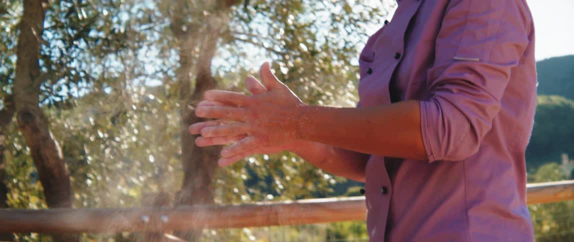 A chef outside clapping his flour covered hands
