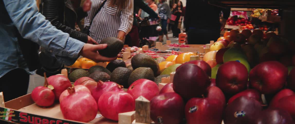 People in a grocery store observing fresh fruit on the street