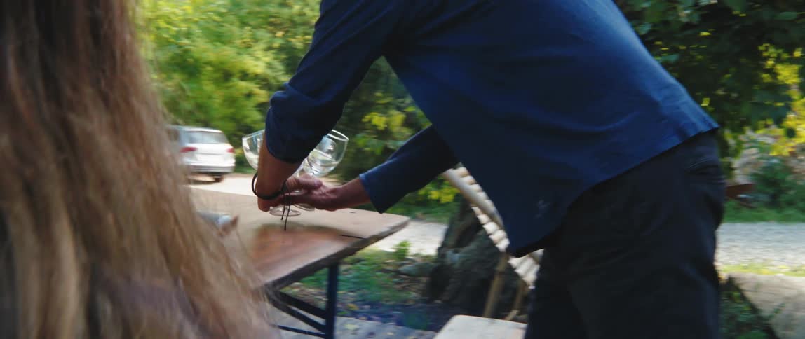 Man arranges stemware on a table in the backyard