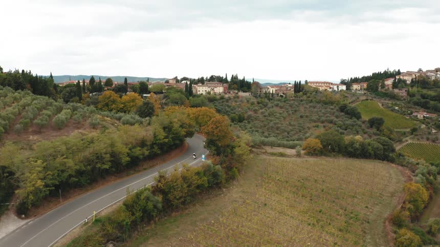 Aerial panorama of a winding street in the middle of fields and urban areas during the day with cloudy sky