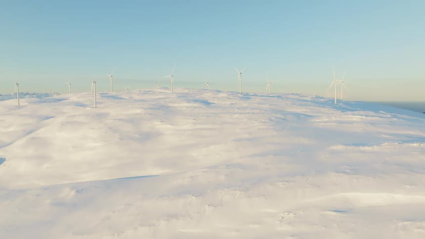 Aerial views of wind power platforms on top of a snow covered mountain