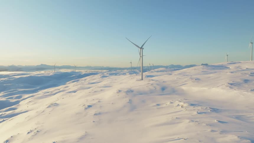 Aerial view of wind turbines on a hill covered in snow
