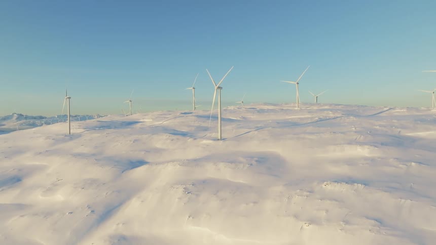 Windmills on a wide open landscape covered in snow on a bright sunny day
