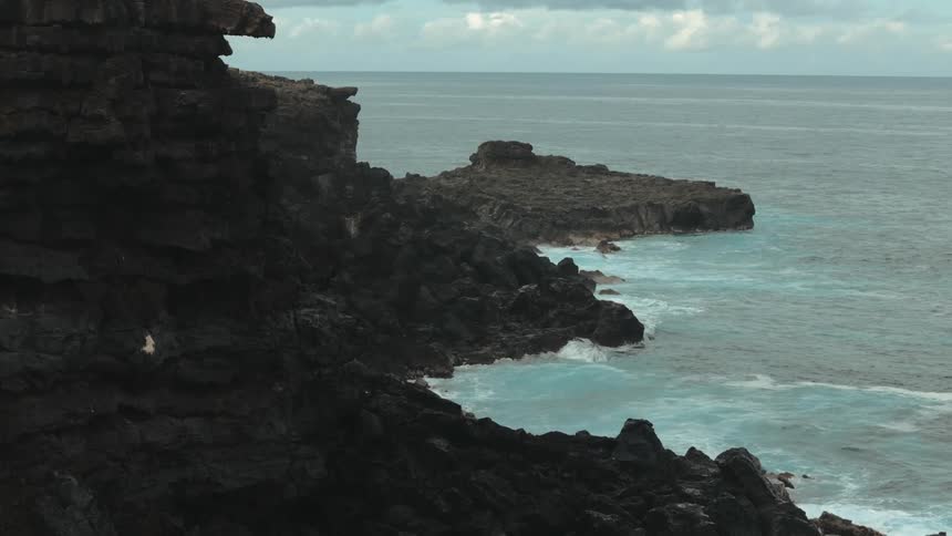 Ocean water crashes against a cliff rock face