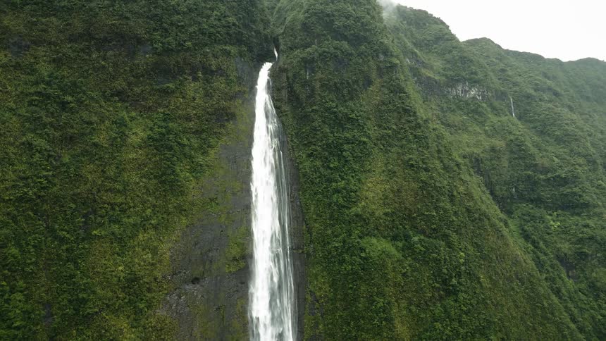 Aerial panorama of a waterfall on a large forested mountain