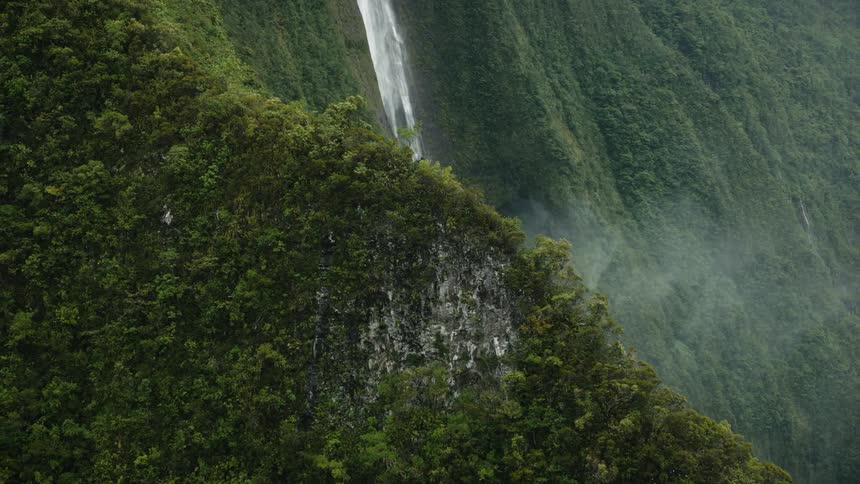 Panorama of a mountain flanked by forests and an extensive waterfall