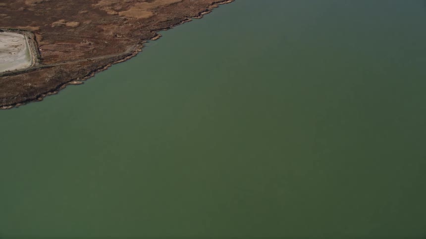 An aerial view of a land in front of a calm and green sea