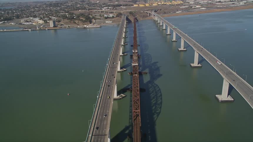 Aerial view of three bridges one with a railway line and two others with vehicle traffic over the sea during the day