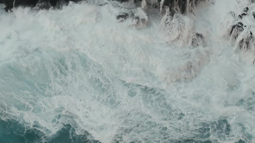 Big waves waves of water crash against a rocky cliff