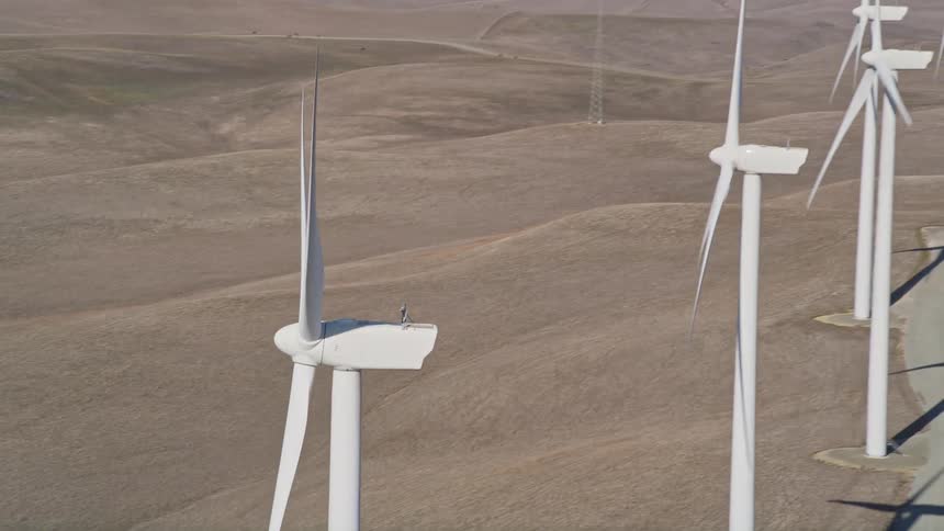 A windmill farm on a vast grassy plain