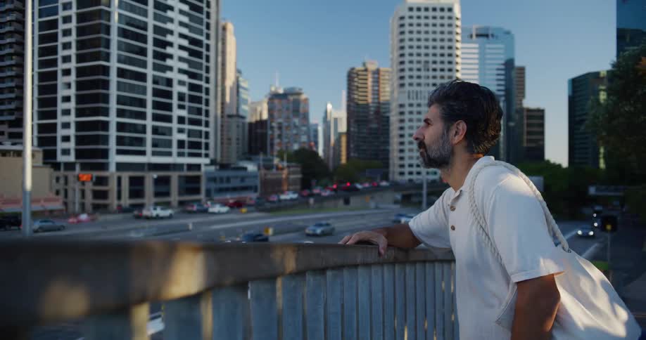 A man stands by a railing looking at a city