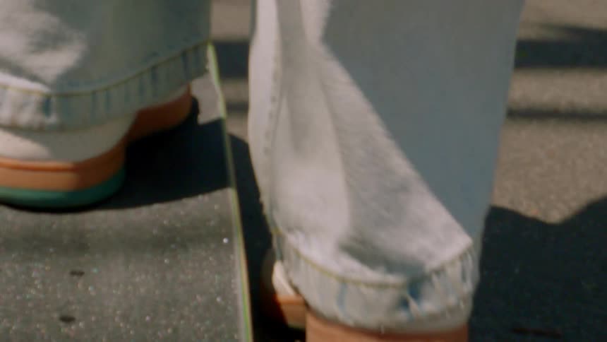 Closeup of a persons legs riding a skateboard on an asphalt