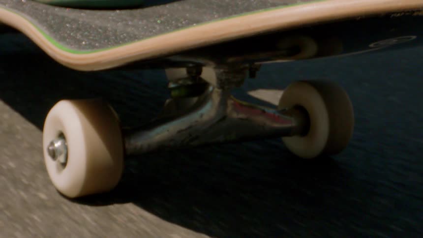 Closeup of the back of a skateboard moving across the asphalt