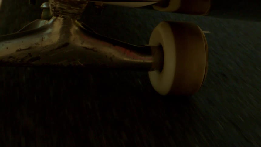 Close up of the wheels of a skateboard spinning on asphalt